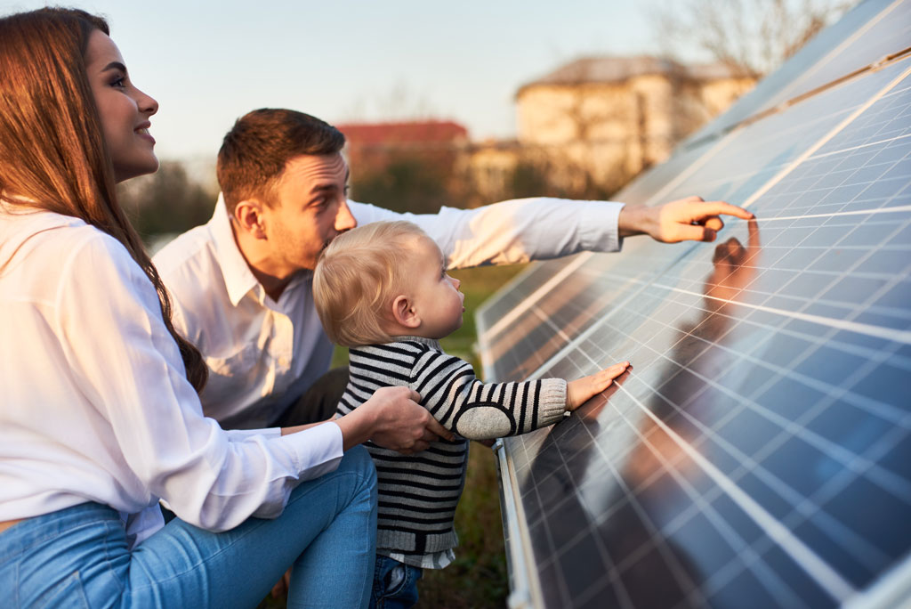 Ehepaar steht mit Kind an Photovoltaikanlage